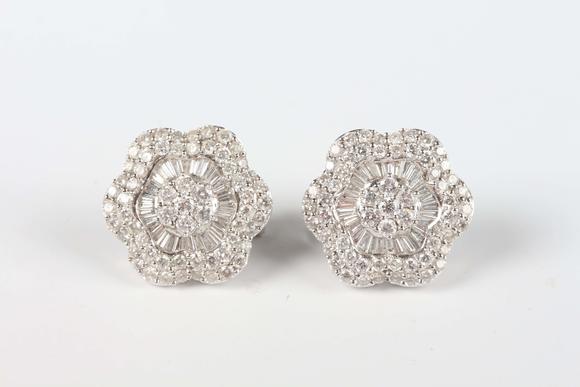 TooveysA pair of white gold and diamond earrings, each in a flowerhead shaped design, mounted with circular and tapered baguette cut diamonds, with post and