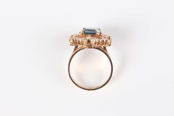 TooveysA gold, blue topaz and diamond cluster ring, claw set with the cut cornered square cut blue topaz within a surround of marquise, baguette and circular