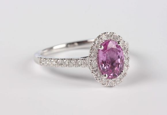 TooveysA platinum, pink sapphire and diamond oval cluster ring, claw set with the oval mixed cut pink sapphire within a surround of circular cut diamonds, be