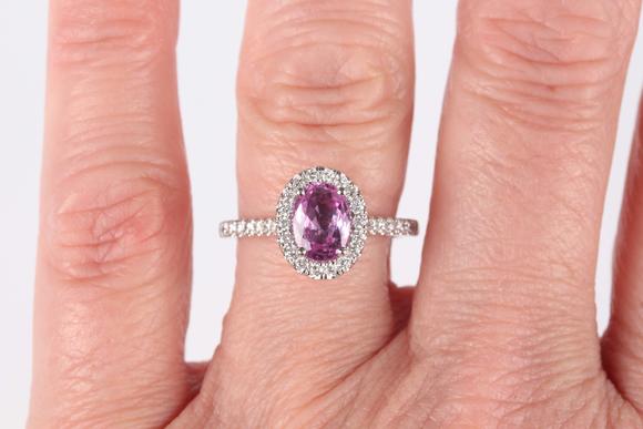 TooveysA platinum, pink sapphire and diamond oval cluster ring, claw set with the oval mixed cut pink sapphire within a surround of circular cut diamonds, be