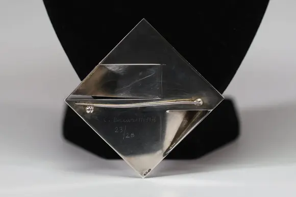 Goldfield Auction sarlsModernist brooch in 925/1000 silver, geometric shape with folded panels in relief, Italian work signed Carlo Lorenzetti, dated 1976.
Limited edition of 28, numbered and signed on the reverse, published by Galleria La Polena, Genoa.
A sculptural aesthetic characteristic of Italian research in the 1970s, in good overall condition.
Condition : Good
Height : 2 cm 
Width : 6 cm
Weight : 32,6 gr