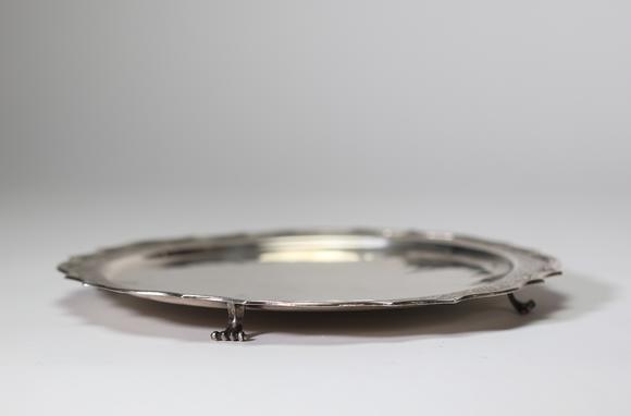Goldfield Auction sarlsAssiette dite volante en argent massif, travail liégeois daté 1724, de forme circulaire à bord contourné et légèrement festonné. Elle repose sur trois