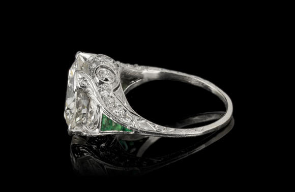 Piguet - H?tel des VentesBague Art Déco platine centrant un diamant taille brillant entouré de diamants taille demi-lune et 8/8 ainsi que d'émeraudes calibréesArt Déco platinum ring set with one center diamond, half-moon and 8/8 cut diamonds and calibrated-cut emeralds