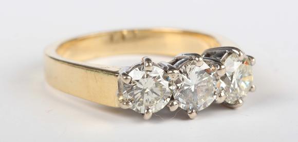 TooveysAn 18ct gold and diamond three stone ring, claw set with a row of ci
