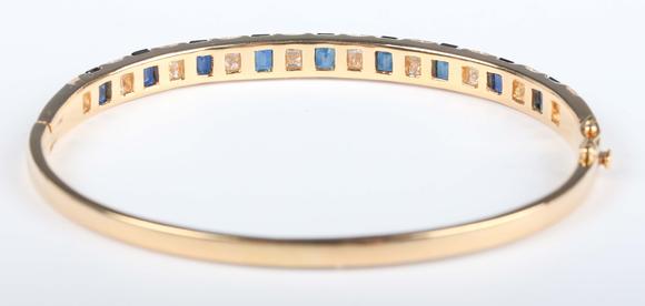 TooveysA gold, sapphire and diamond bangle, mounted with a row of nine cut