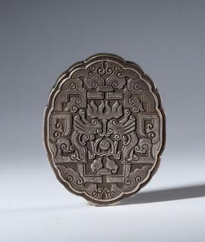 A decorative element in embossed and engraved silver with a through-hole for hanging. Richly decorated with schematic dragons and clouds. China, 19th century.