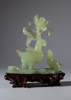 Green jade sculpture on a wooden base depicting a pair of birds and a large flower. China, 20th century.