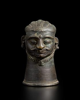 A small brass Shiva lingam cover,?
Western Deccan, 19th century,?

with almond bulging eyes under marked eyebrows, his full lips under a serpenti
