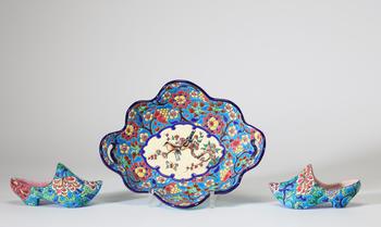 émaux de Longwy, ensemble comprenant un plat polylobé à prises latérales et deux sabots décoratifs en fa?ence émaillée à décor floral polychrome et ré