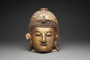 TêTE DE GARDIEN "LOKAPALA" en bois laqué et doré, la tête coiffée d'un casque orné de quatre médaillons en têtes de diamants. (Q...