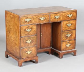 A 20th century George I style walnut kneehole desk with overall feat